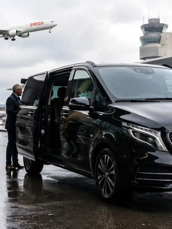 Alpinum Taxi Mercedes Minibus 4x4 collecting passengers at Zurich Airport, driver at the open sliding door