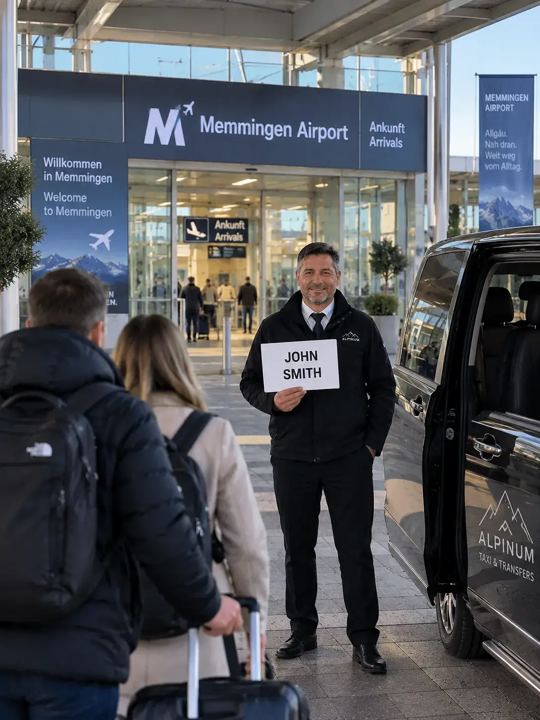 Alpinum Taxi driver with a name sign beside the minibus at Memmingen Airport arrivals, meeting guests for a private transfer to the Arlberg