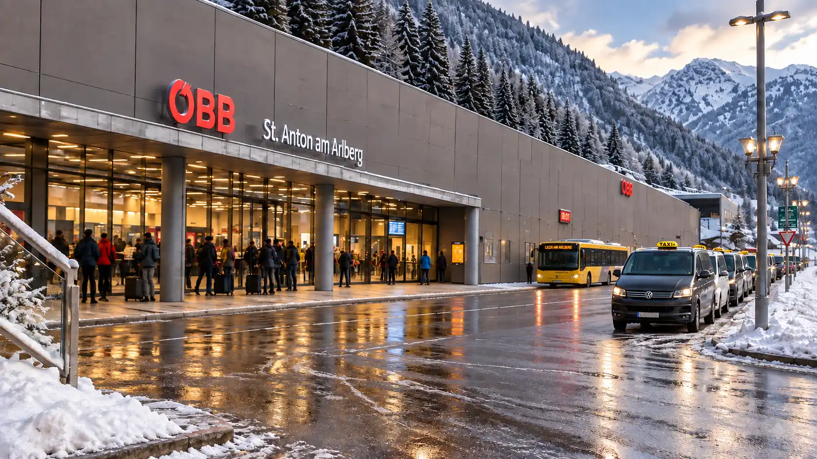 Alpinum Taxi: taxis at the rank outside St. Anton am Arlberg railway station at dusk, travellers with luggage at the entrance